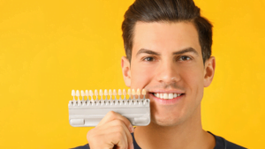 Man holding a tray of fake teeth with different colours