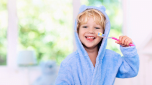 Child in a bathrobe holding a toothbrush.